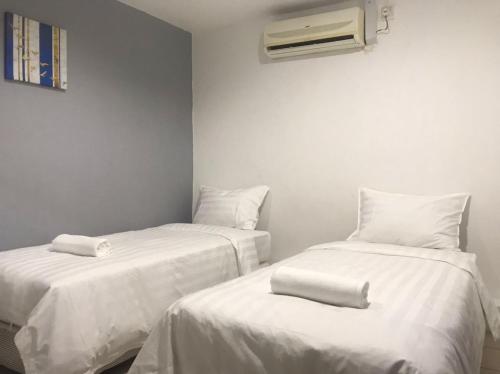 a room with two beds with white sheets and a heater at Hotel Seroja in Labuan