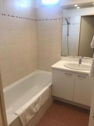 une salle de bain avec une baignoire et un lavabo dans l'établissement ZenBNB - ISIS - Piscine - Balcon - 4 Pers, à Nangy