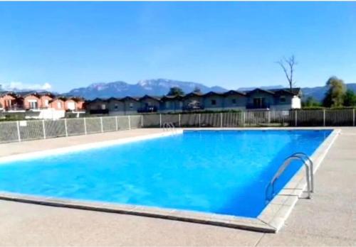 a large blue swimming pool with houses in the background at ZenBNB - ISIS - Piscine - Balcon - 4 Pers in Nangy