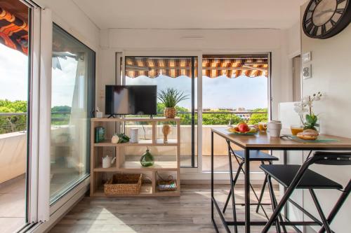 une salle à manger avec une table et une grande fenêtre dans l'établissement Rêves Ensablés * Clim * Proche Mer * Terrasse * Port Camargue, au Grau-du-Roi