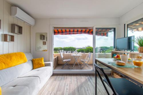 een woonkamer met een bank en een tafel bij Rêves Ensablés * Clim * Proche Mer * Terrasse * Port Camargue in Le Grau-du-Roi