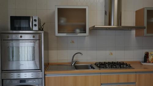 a kitchen with a sink and a stove and a microwave at Bridge's House - a 50 mt dalla spiaggia e da tutti i servizi! in Pescara