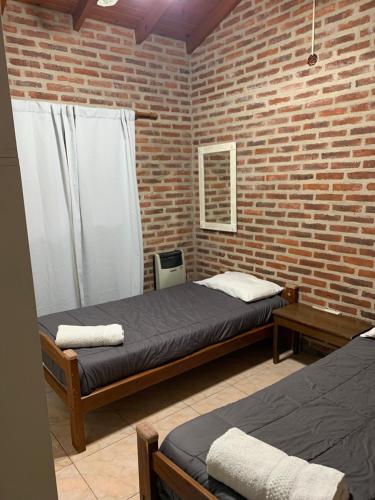 a bedroom with two beds and a brick wall at Casa Mali in Azul