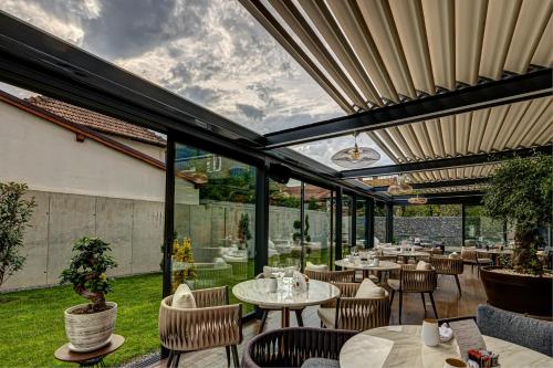a restaurant with tables and chairs and windows at Hotel Vibre in Cluj-Napoca