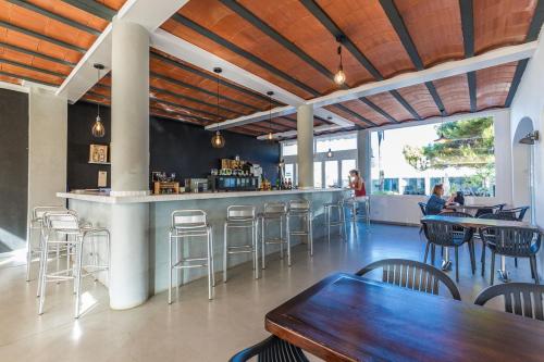 un restaurante con un bar con mesas y sillas en Vibra Caleta Playa Apartmentos-3SUP, en Sa Caleta