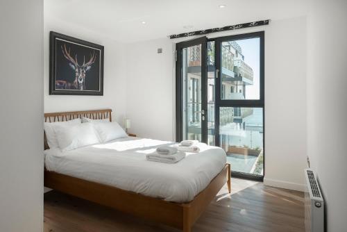 a bedroom with a bed and a large window at Beachside: New two bedroom apartment with parking in Kent