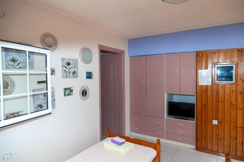 a kitchen with pink cabinets and a table and a window at Liakos' Apartments in Vasiliká