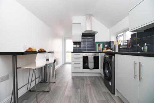 a kitchen with white cabinets and a washer and dryer at Modern Guesthouse, Fast Wi-Fi, Street Free Parking, Central, Fully Equipped in Cardiff