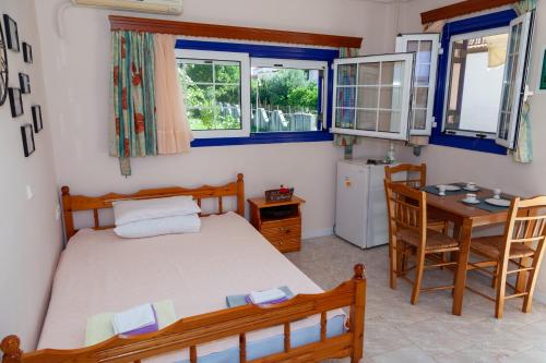 a bedroom with a bed and a table and a desk at Liakos' Apartments in Vasiliká