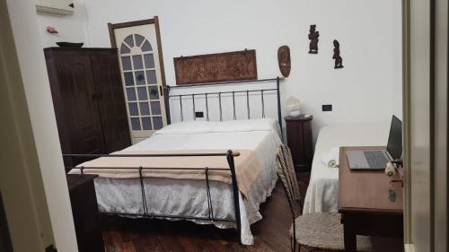 a bedroom with a bed and a desk with a laptop at Villa Pantarei in Pozzallo