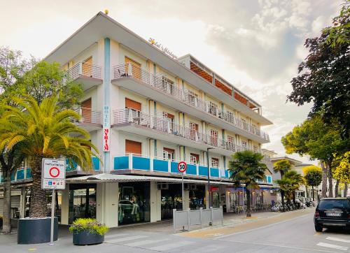 a building on a street with palm trees in front of it at Hotel Myriam in Lignano Sabbiadoro