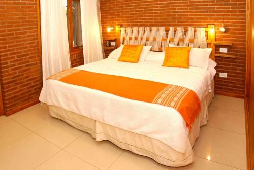 1 dormitorio con 1 cama grande con almohadas de color naranja y blanco en Escondida en el Bosque en Mar de las Pampas