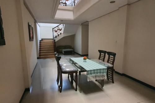 uma sala de jantar com uma mesa e cadeiras e uma escadaria em OYO 93202 Pentagon Homestay Syariah em Surabaya