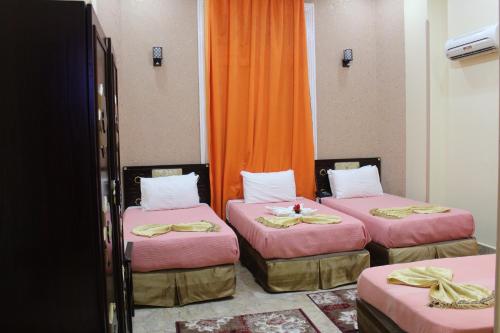 three beds in a room with orange curtains at City View Museum Hotel in Cairo