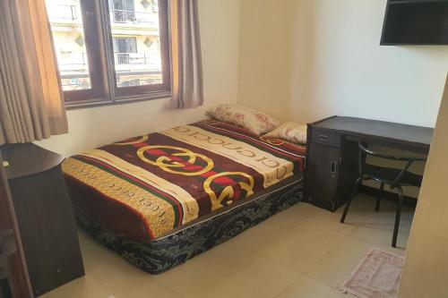 a small bedroom with a bed and a desk at OYO 93202 Pentagon Homestay Syariah in Surabaya