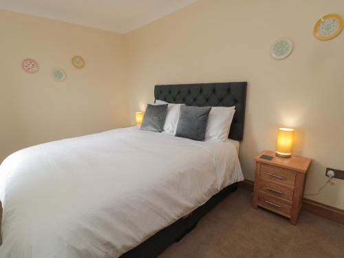 een slaapkamer met een groot bed en 2 lampen op een nachtkastje bij Whinny Cottage in Alnwick