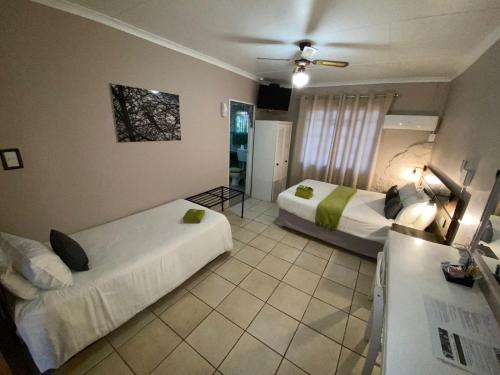 a hotel room with two beds and a ceiling fan at The Ultimate Lodge in Louis Trichardt