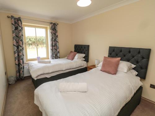 two beds in a room with a window at Smithy Cottage in Alnwick
