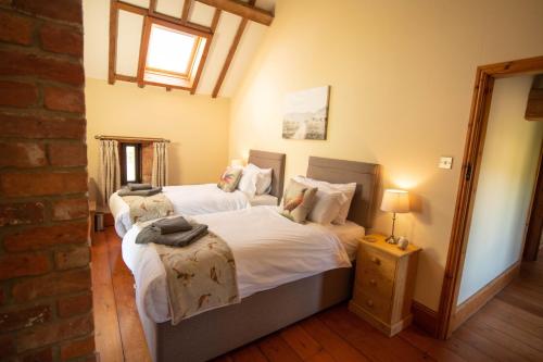 a bedroom with two beds and a lamp on a table at The Threshing Barn in Woodhall Spa