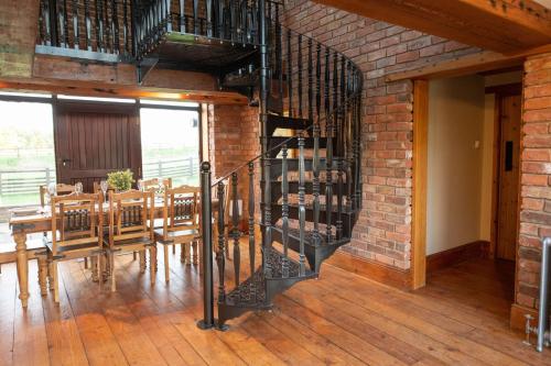 a room with a brick wall and a spiral staircase at The Threshing Barn in Woodhall Spa