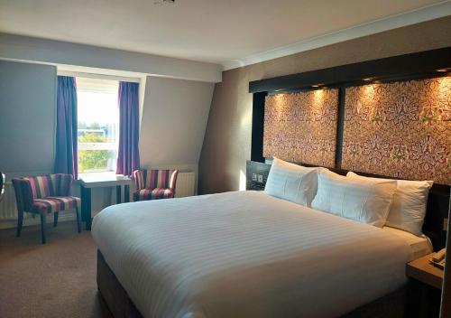 a hotel room with a large bed and chairs at Flannery's Hotel in Galway