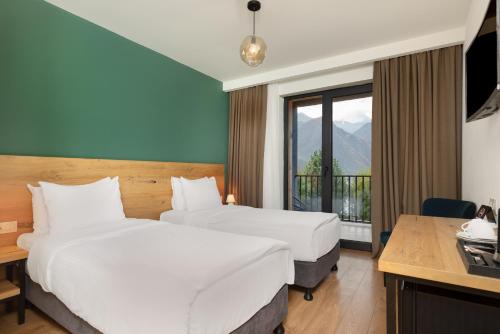 a hotel room with two beds and a balcony at Intourist Kazbegi in Stepantsminda