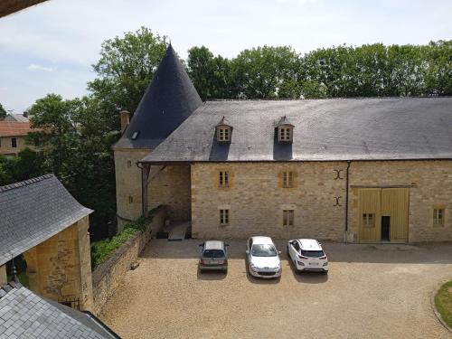 tres coches estacionados frente a un gran edificio en 3 Gîtes avec piscine au Château de Charbogne, 