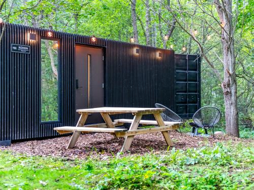 a wooden picnic table in front of a black building at Chic Sauna Cabin Near the Sea - KOHIN Cabin Nº02 in Tsitre