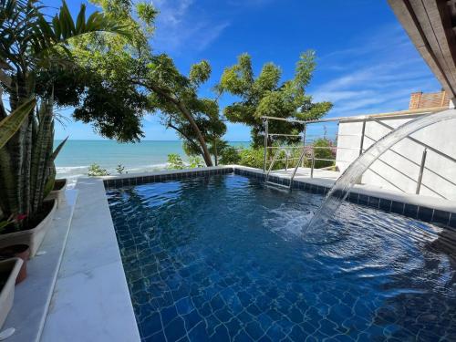 a swimming pool with a water fountain in front of the ocean at Pousada ResDelMar in Baía Formosa