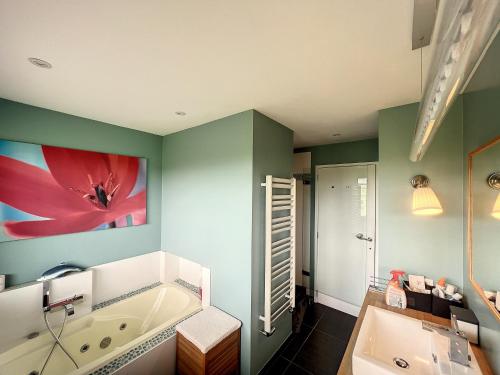 ein Badezimmer mit Badewanne und ein großes Wandgemälde in der Unterkunft Suite duplex salon-bureau & chambre en mezzanine in Opprebais