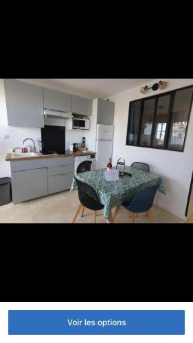 une cuisine avec une table et des chaises dans une pièce dans l'établissement Bel appartement climatisé refait à neuf 100 m de l'océan et toutes commodités 3 e étage sans ascenseur, à Seignosse