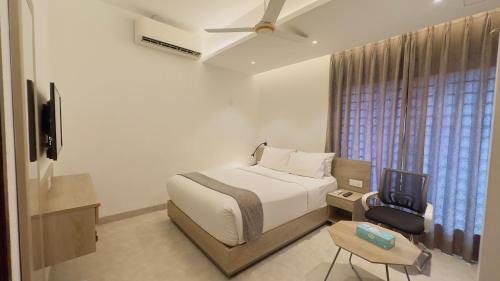 Schlafzimmer mit einem Bett, einem TV und einem Stuhl in der Unterkunft Priyo Nibash Stylish Residential Hotel in Dhaka