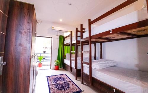 リシケーシュにあるManzil Hostelのラグ付きの二段ベッド3台が備わる客室です。