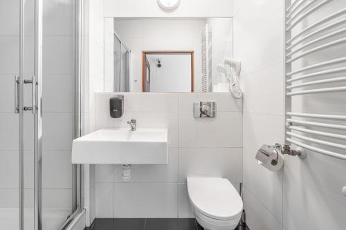 a white bathroom with a toilet and a sink at Dom Pracy Twórczej in Uniejow