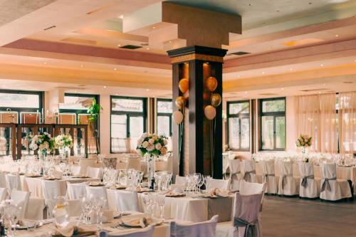 - une salle de banquet avec des tables et des chaises blanches dans l'établissement Complex Praveshki Hanove, à Pravets