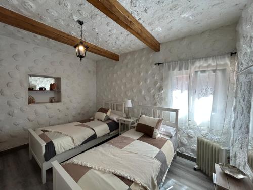 two beds in a bedroom with white walls and wooden ceilings at Casa Rural Juli in Santa Cruz de Tenerife