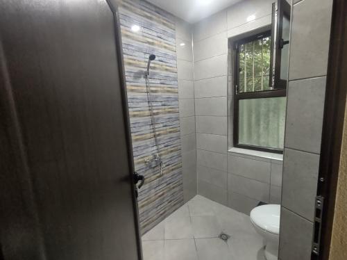 uma casa de banho com um chuveiro, um WC e uma janela. em Cozy Rooms Panagyurishte em Panagyurishte