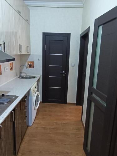 a kitchen with a black door and a white washing machine at Квартира in Bishkek