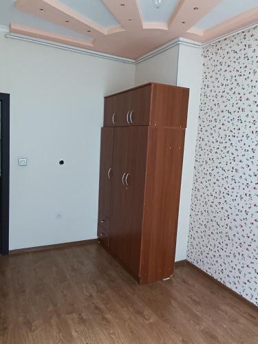 a large wooden cabinet in a room with white walls at Квартира in Bishkek