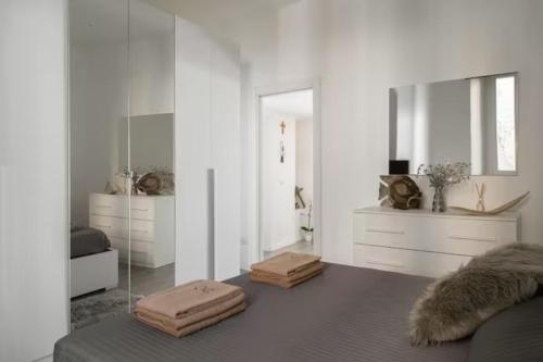 Cette chambre blanche comprend un lit et un miroir. dans l'établissement Frontelago - Eleganza in una vista da sogno, à Rezzonico
