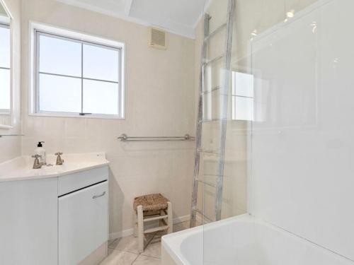 a white bathroom with a shower and a sink at Sea Blue Heaven in Tutukaka