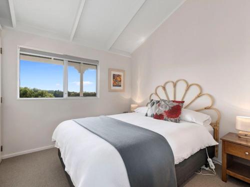 a white bedroom with a large bed and a window at Sea Blue Heaven in Tutukaka