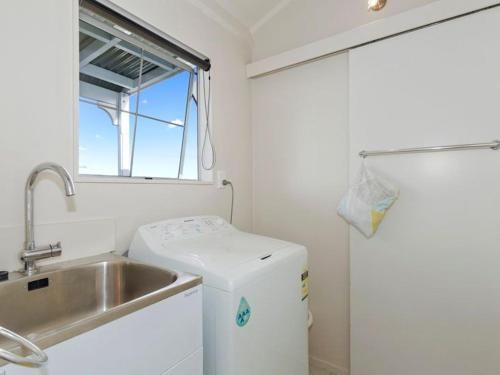 a small kitchen with a sink and a washing machine at Sea Blue Heaven in Tutukaka