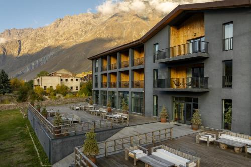 un edificio con una terraza con mesas y bancos en Intourist Kazbegi en Kazbegi