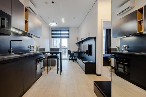 a kitchen with black cabinets and a living room at WOL 121 by Ribas in Odesa