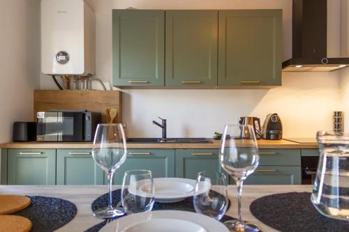 une cuisine avec des placards verts et une table avec des verres à vin dans l'établissement ZenBNB / ZEBRA / 2 min. Gare /Tramway / 3Pers/ Stationnement, à Annemasse