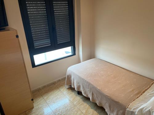 um pequeno quarto com uma cama e uma janela em Hostal Restaurant El Poligono em Valência