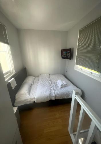 Cama pequeña en habitación con 2 ventanas en Quirky Studio Camden, en Londres