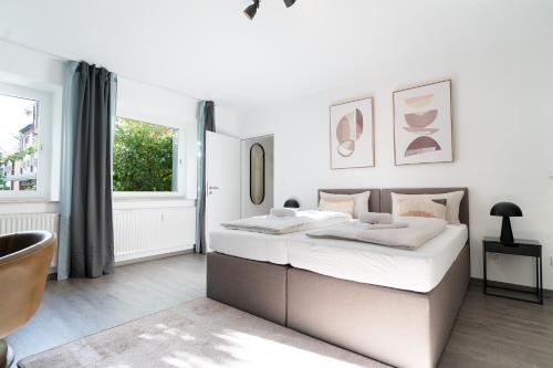 a white bedroom with a large bed and a window at Blumenhaller Boardinghouse in Osnabrück