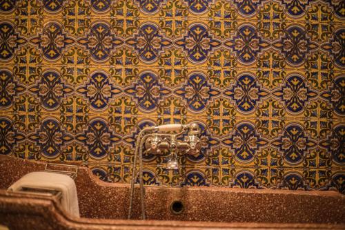 un baño con una pared dorada y azul estampada en El Palacio de San Benito, en Cazalla de la Sierra